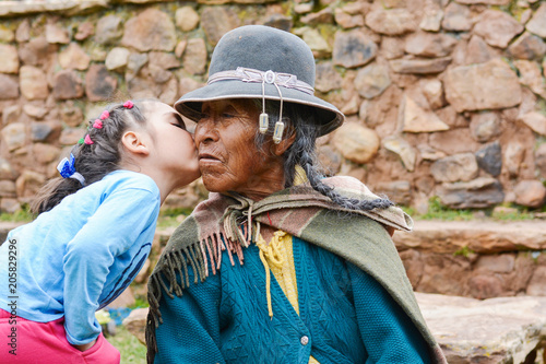 Little latin girl kissing her native american grand grandmother. photo