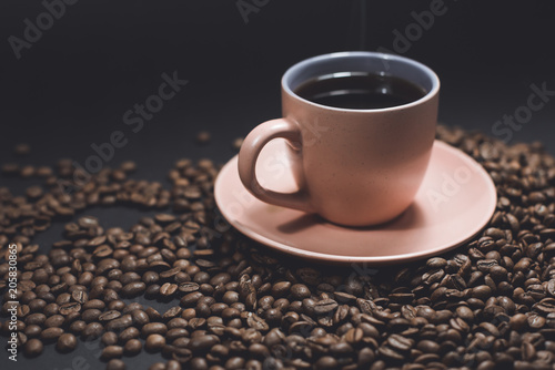 Cup of black coffee and roasted coffee beans.