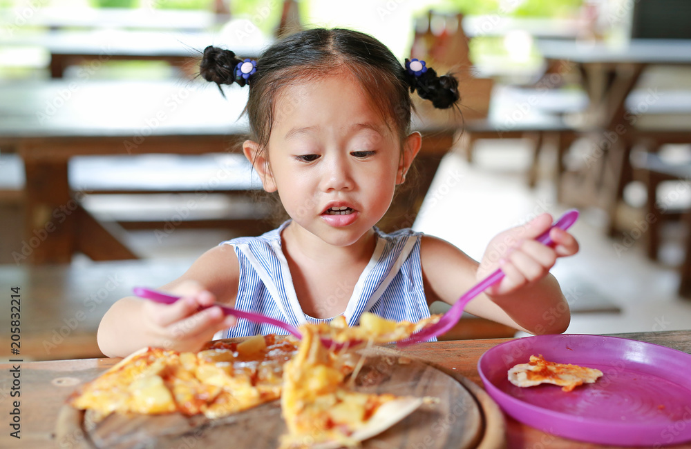 Little child girl enjoy eating pizza.