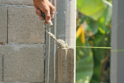 Bricklayer worker installing cement blocks wall