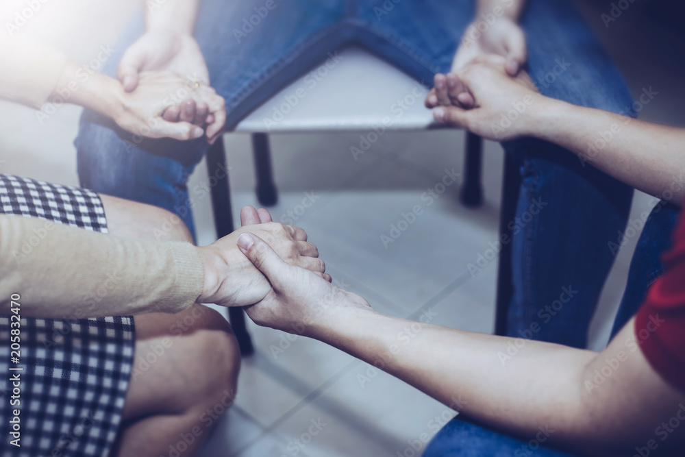 Fototapeta premium Christian friends holding hands and praying together around wooden table ,small prayer group in church, christian background with copy space for your text.