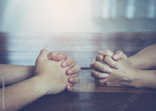 Two Christian friends  praying together around wooden table ,small prayer group in church, christian background with copy space for your text.