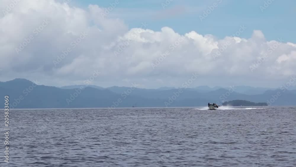 Indonesia. Motor boat swims quickly in the sea against the background of a tropical island. Slow motion Indonesia. Motor boat swims quickly in the sea against the background of a tropical island. Slow motion