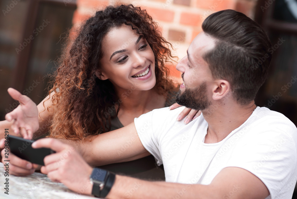 Obraz premium Happy loving couple using a smartphone sitting in terrace