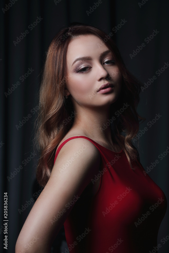 Charming brunette in a red dress posing on a black background. Charming brunette in a red dress posing on a black background.