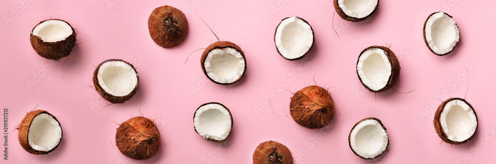 Fototapeta premium Wzór z dojrzałymi kokosami na różowym tle. Widok z góry. Kopia przestrzeń. Projekt pop-artu, koncepcja kreatywnego lata. Połowa orzecha kokosowego w minimalistycznym stylu świeckich.