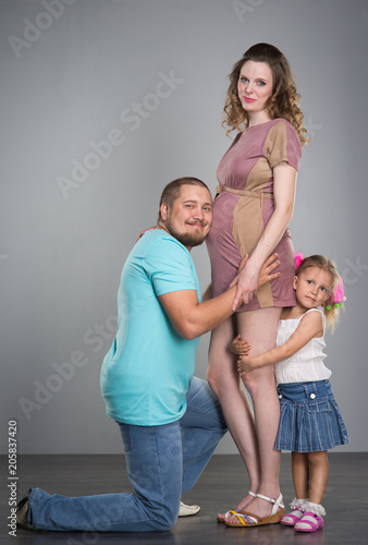 Husband and pregnant wife on gray background
