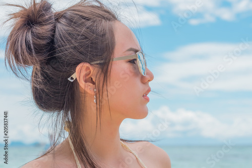 Beautiful young woman in sexy bikini standing at sea beach