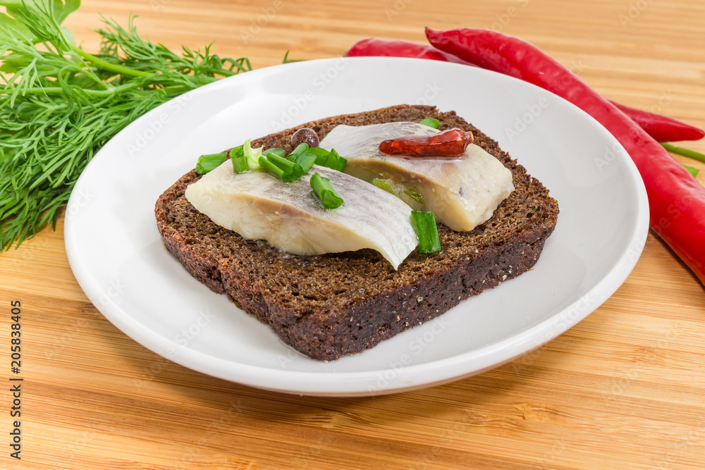 Open sandwich with pickled herring slices on brown bread closeup Open sandwich with pickled herring slices on brown bread closeup