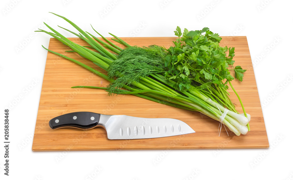 Bunches of green onion, dill, parsley, knife on cutting board