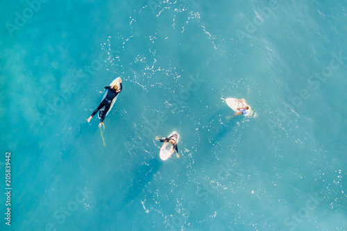 Three surfers in a calm ocean, top view