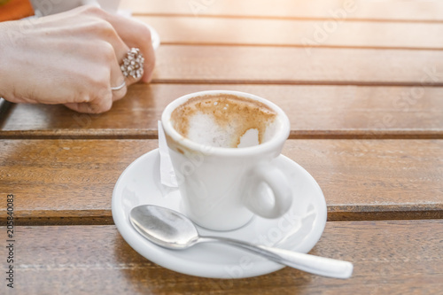 empty cup of coffee on a table near a woman's hand