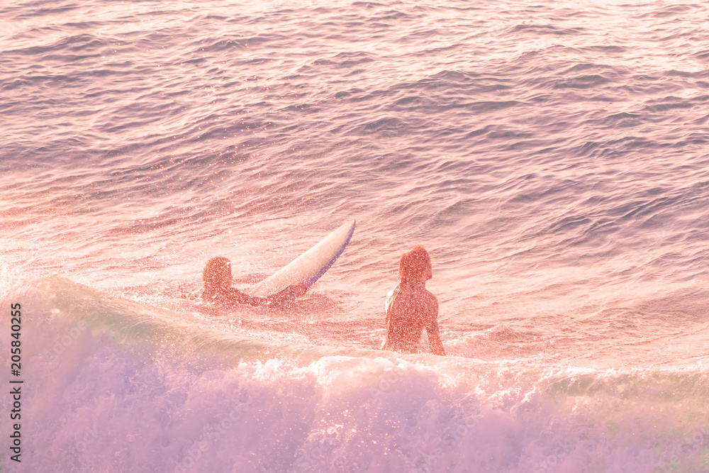 Fotografie Two surfers in the ocean at sunset