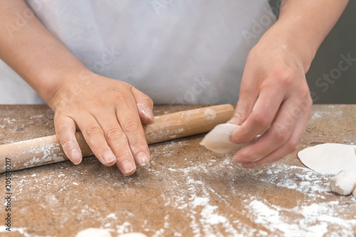 The cook rolls a piece of dough with a rolling pin
