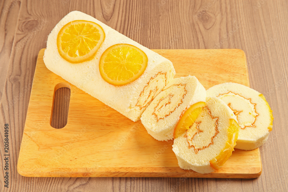 Orange swiss roll on the wooden cutting board     