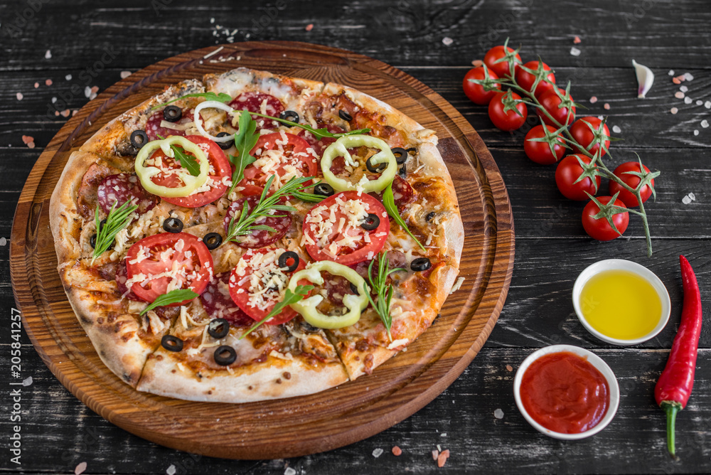 Vegetables, mushrooms and tomatoes pizza on a black wooden background. It can be used as a background