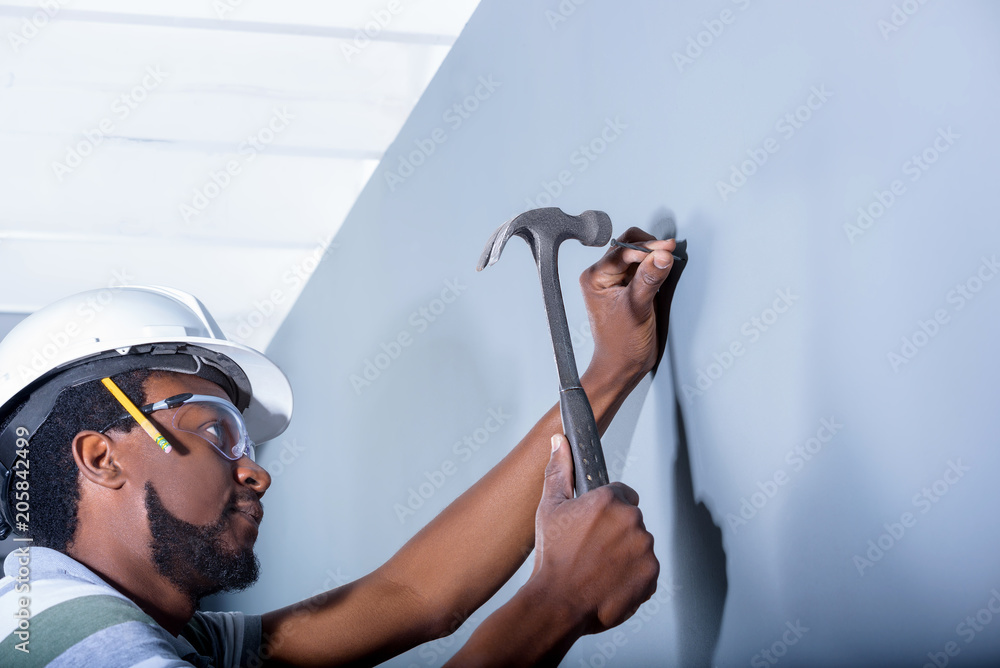 Carpenter hammering nail into the wall Stock Photo | Adobe Stock