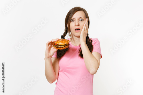 Young beautiful woman in pink t-shirt with braids holding in hands burger isolated on white background. Proper nutrition or American classic fast food. Copy space for advertisement. Advertising area.