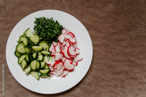 pieces of cucumber and fresh radish on a white plate photo