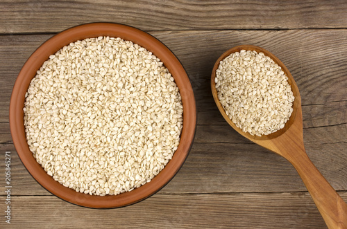 Sesame in a bowl on wooden background with a wooden spoon