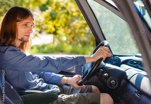 Bored young man with long hair driving car © Voyagerix