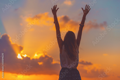 Billede på lærred Girl with arms wide open enjoying sea / ocean scenery in sunset.