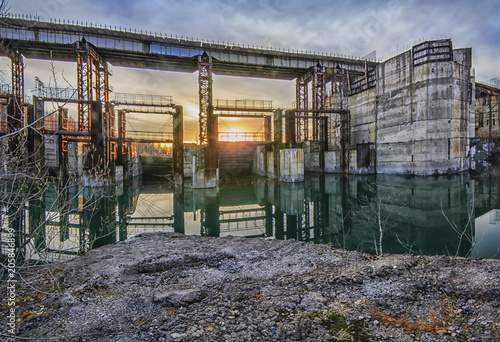 Obraz na płótnie Huge abandoned industrial building on the river damaged hydroelectric sunset view w salonie