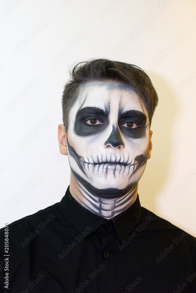 man in make-up Halloween. drawing a vampire, skeleton on his face. Close-up photo. man in make-up Halloween. drawing a vampire, skeleton on his face. Close-up photo.