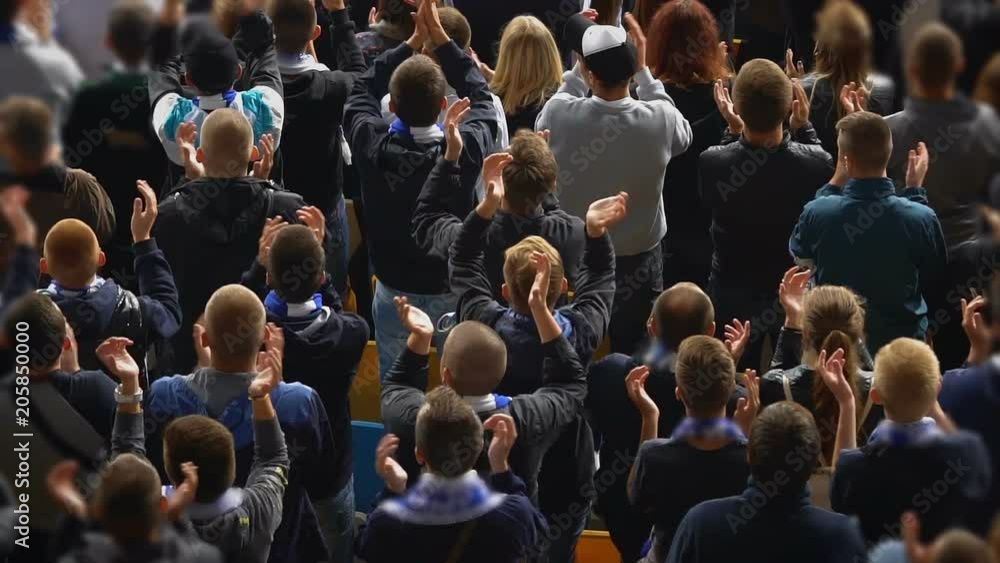Fans at stadium clapping their hands in slow motion, watching sporting