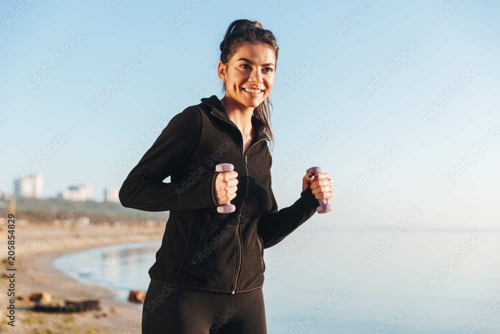 Pretty young sportsgirl doing exercises with small dumbbells Pretty young sportsgirl doing exercises with small dumbbells