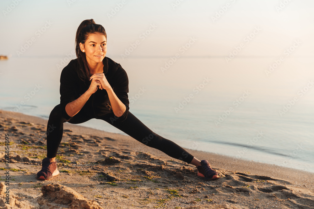 Smiling young sportswoman doing stretching Smiling young sportswoman doing stretching