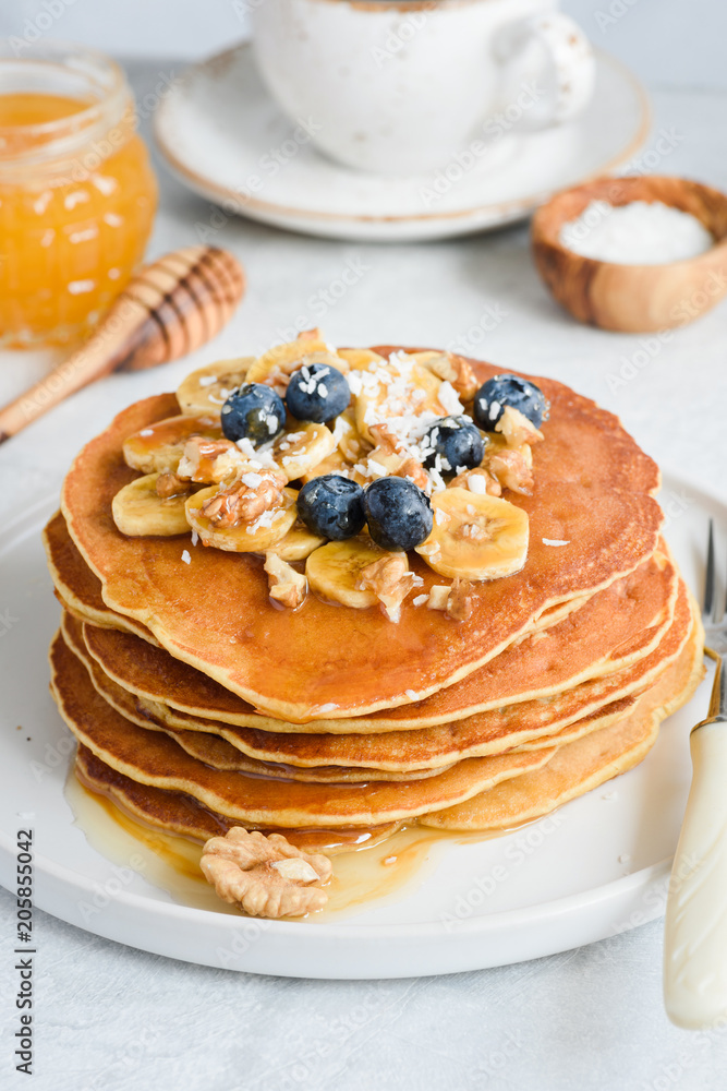 Stack of tasty pancakes with banana, blueberry, walnuts and honey Stack of tasty pancakes with banana, blueberry, walnuts and honey