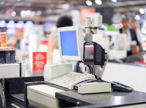 Cash desk terminal  with cashiers and customers on blurry background