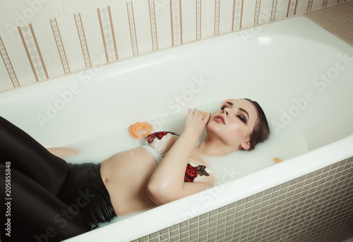 Sensual blonde model with bright makeup. wearing lace bra  takes a bath with milk