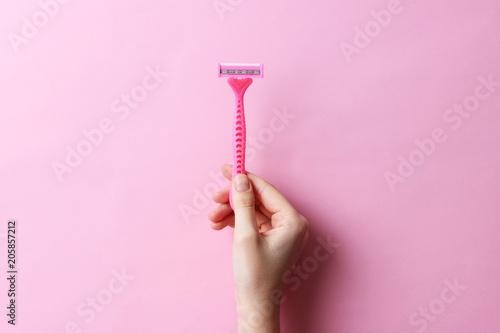 razor in a female hand on a colored background. Removal of unwanted hair. minimalism, the top