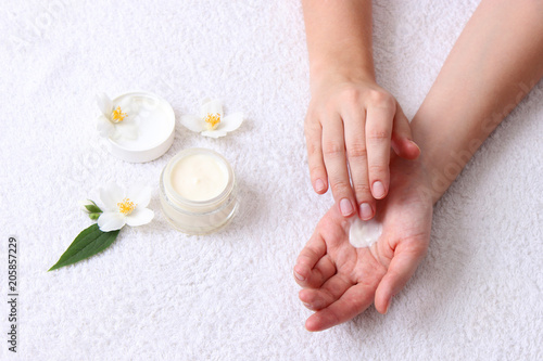 girl smears her hands cosmetic cream on the background of a towel. skin care, elastic and young skin of the hands. top view. 