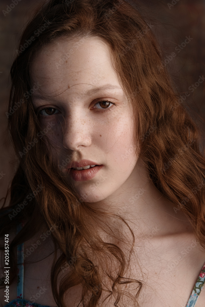 Dramatic portrait of a young cute redhead teenage girl with curly haircut in the studio. Dramatic portrait of a young cute redhead teenage girl with curly haircut in the studio.