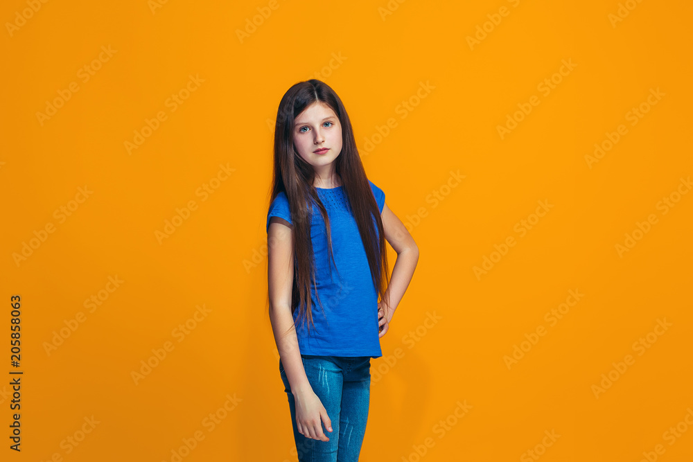 Obraz premium The happy teen girl standing and smiling against orange background.