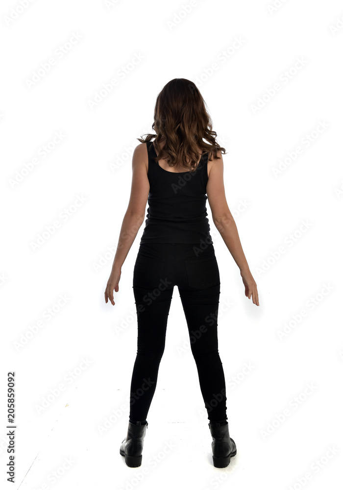 full length portrait of brunette girl wearing black singlet, jeans jeans and boots. standing pose, with back view. isolated on white studio background. full length portrait of brunette girl wearing black singlet, jeans jeans and boots. standing pose, with back view. isolated on white studio background.