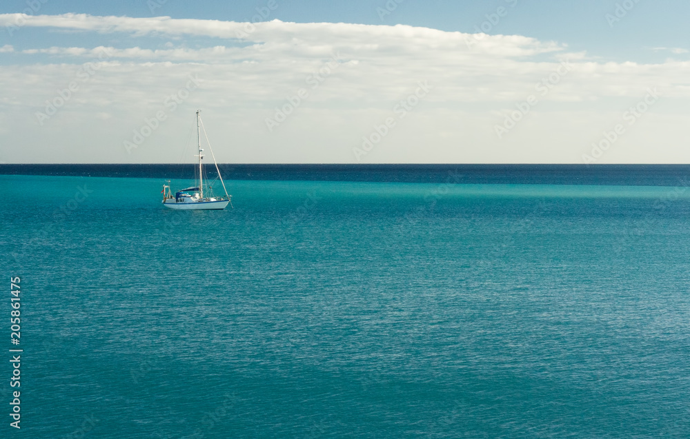Blue Atlantic Ocean with white yacht on the horizon
