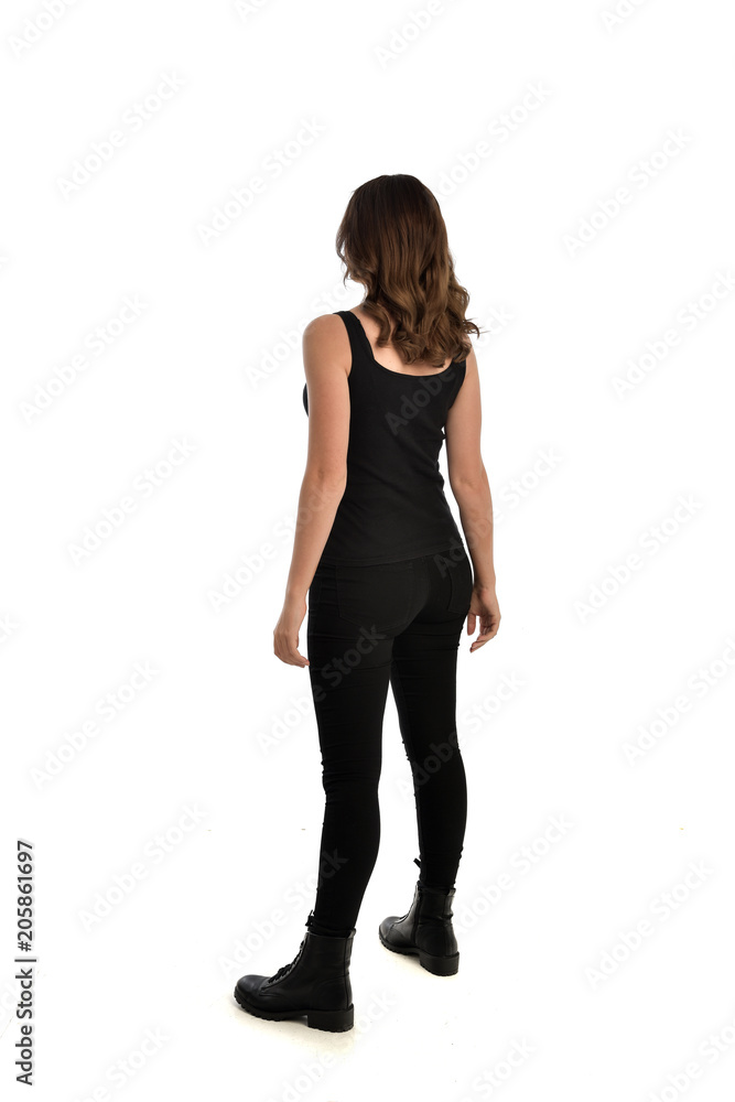 full length portrait of brunette girl wearing black singlet, jeans jeans and boots. standing pose, with back view. isolated on white studio background. full length portrait of brunette girl wearing black singlet, jeans jeans and boots. standing pose, with back view. isolated on white studio background.