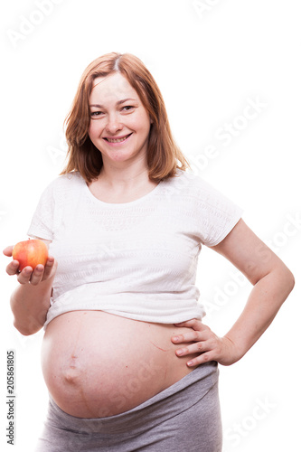 Beautiful preganant woman holding a red apple in her hands isolated over white background photo