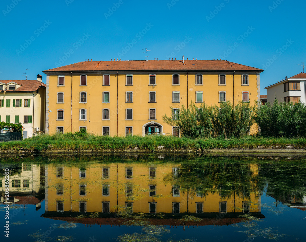 Historic house reflecting on the Naviglio Pavese, a canal that connects the city of Milan with Pavia, Italy.