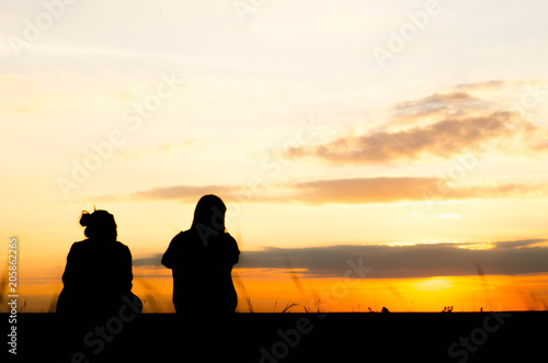 The silhouette of a woman is talking lazily in the evening when the sun is falling.