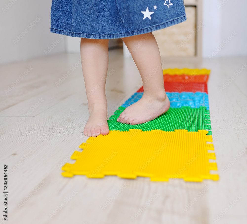 Toddler on baby foot massage mat. Exercises for legs on orthopedic