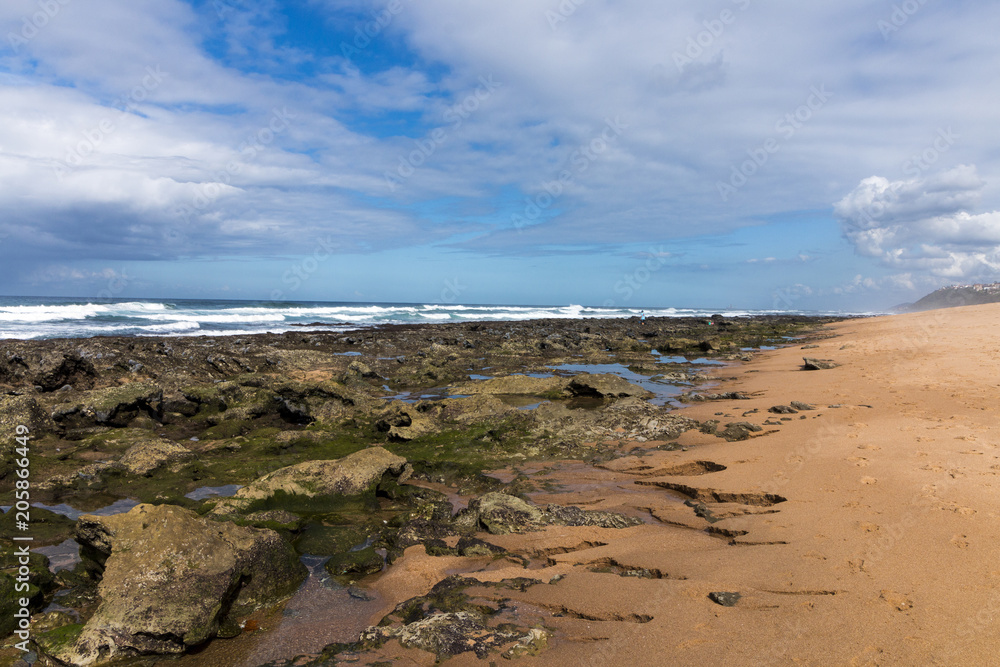 Rocky Beach Waves and Ocean Against Blue Cloudy Skyline