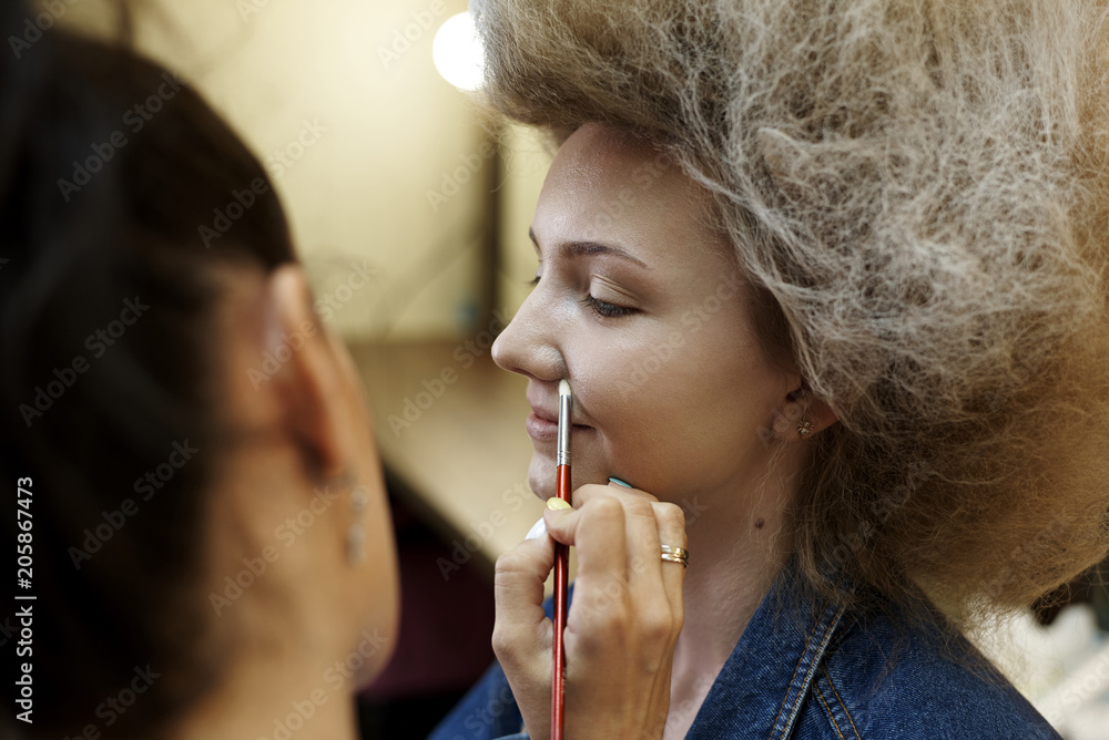 Girls with a lush hairstyle make-up artist makes professional make-up. Girls with a lush hairstyle make-up artist makes professional make-up.