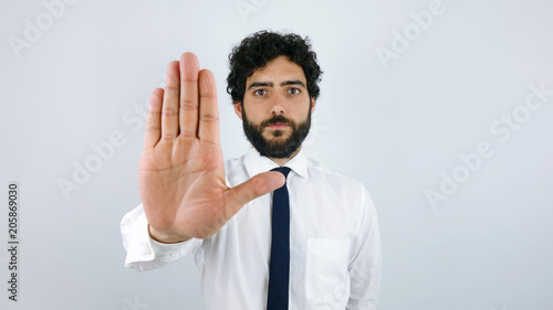Portrait of handsome man whit shirt and tie showing stop sign over gray background.