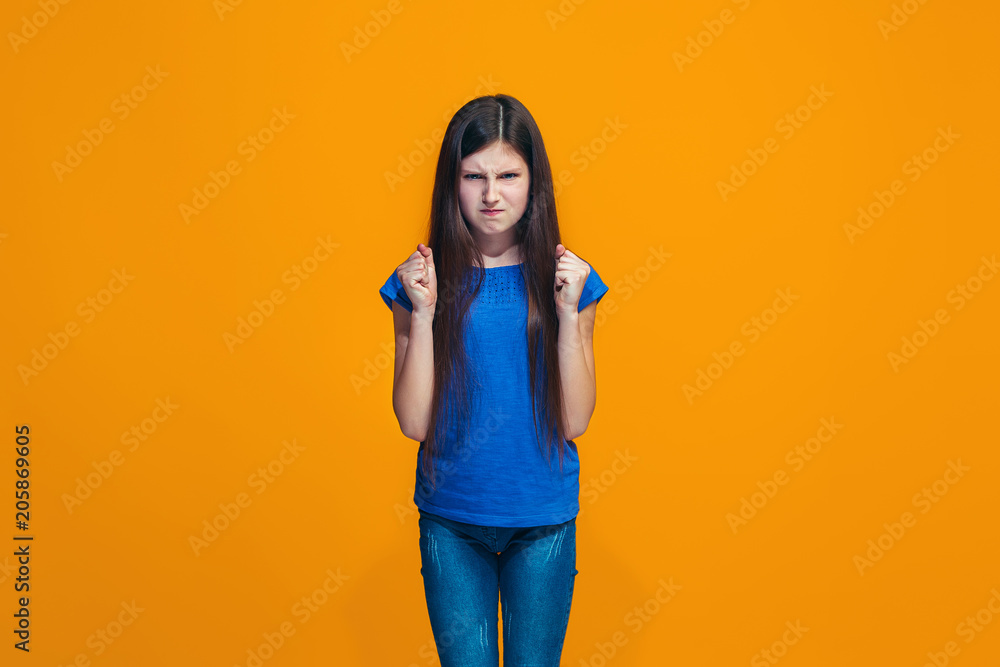 Portrait of angry teen girl on a orange studio background Portrait of angry teen girl on a orange studio background