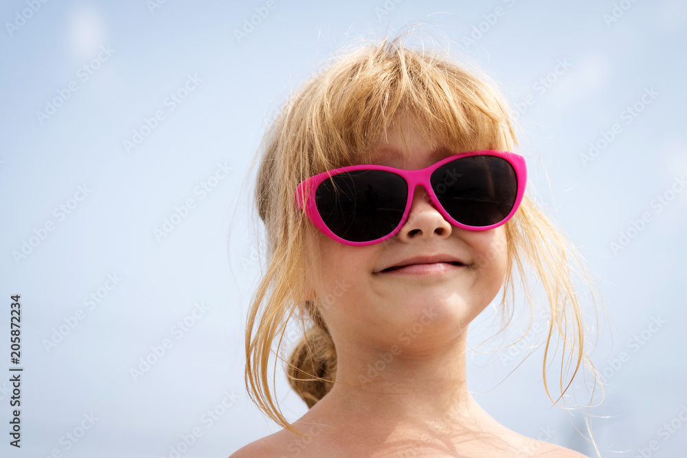 large portrait of a little pretty smiling girl in pink sunglasses on the sky background large portrait of a little pretty smiling girl in pink sunglasses on the sky background